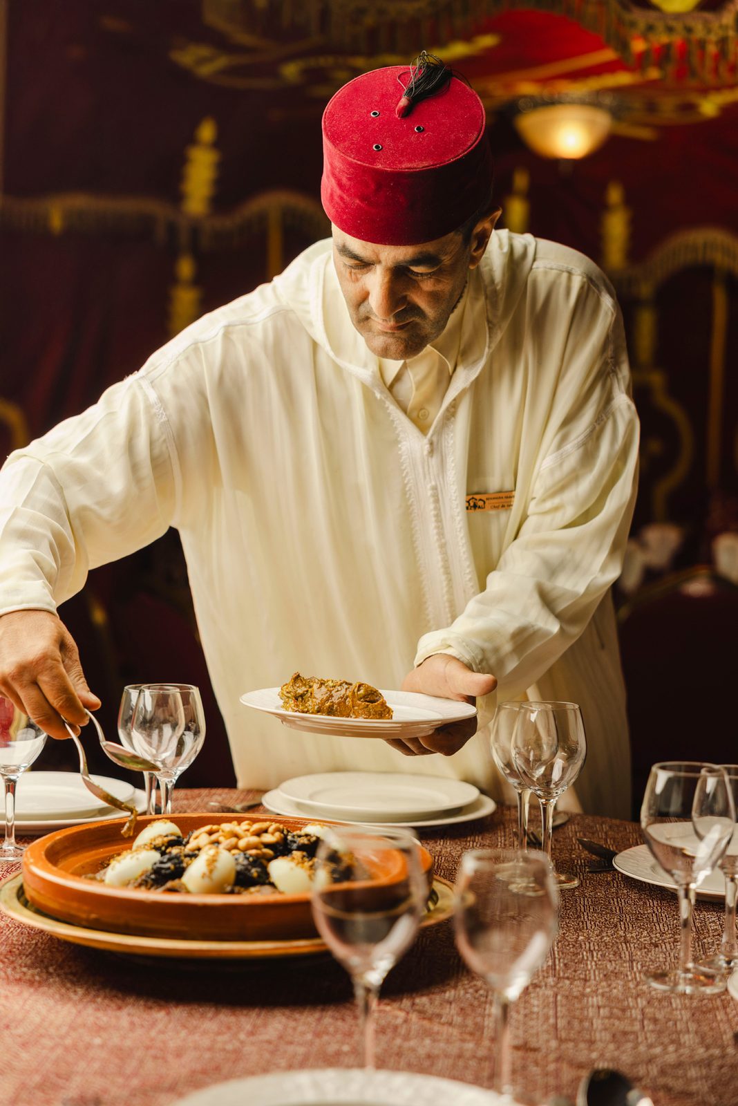 Waiter in a red fez serving dinner at Chez Ali